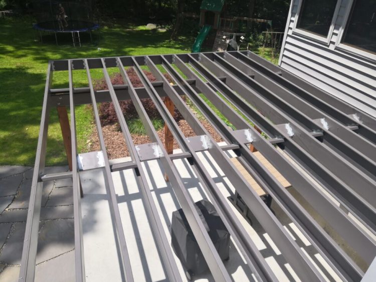 Professional installation of galvanized steel deck framing showing perfectly straight joists with powder-coated finish and consistent spacing for long-term durability